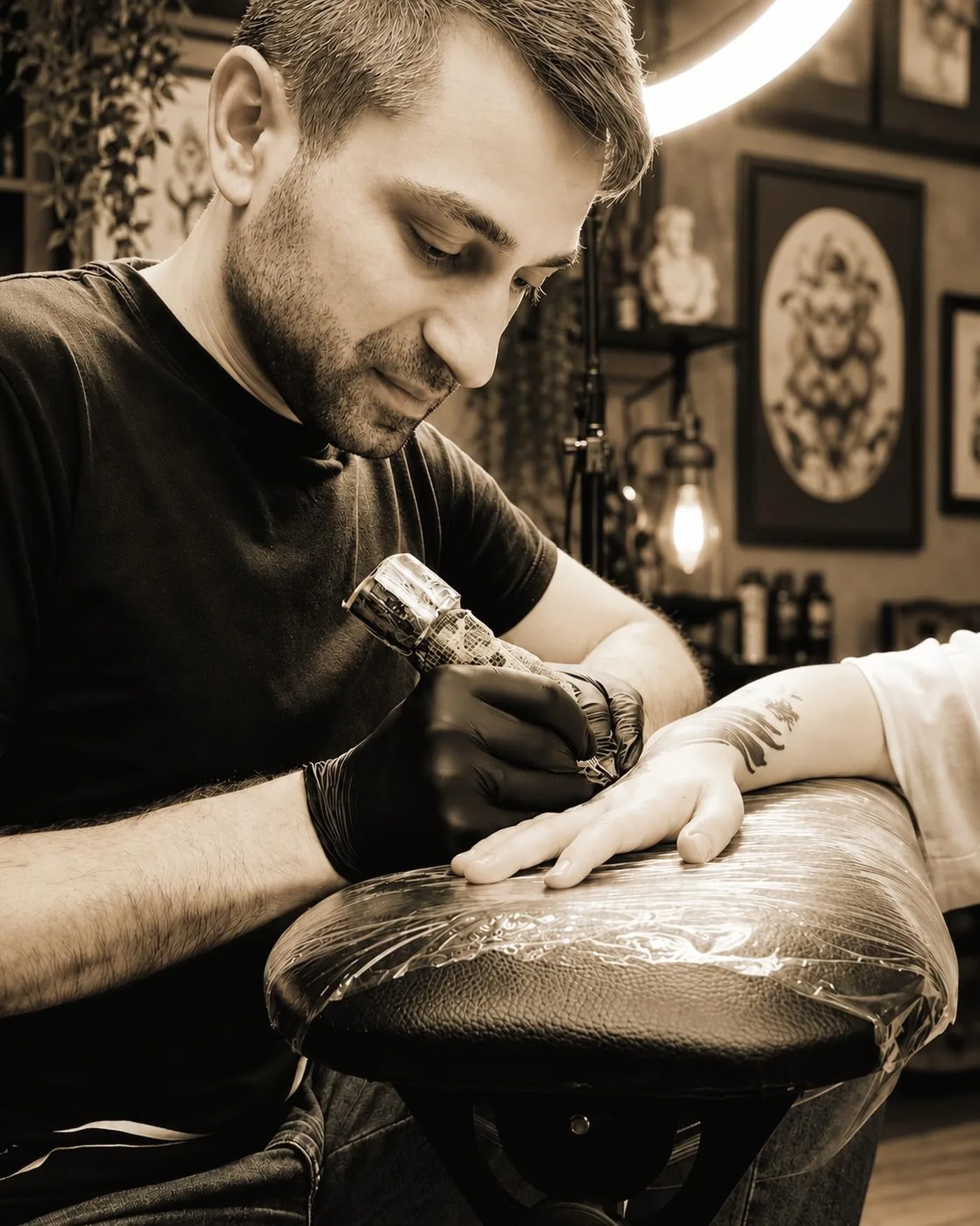 Bacho Lomidze, Inhaber von Ink Lomi, tätowiert konzentriert im warm beleuchteten Atelier