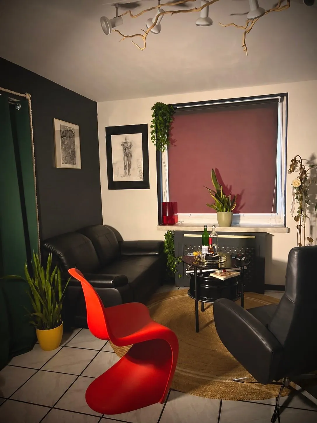 Wartebereich im Tattoo Atelier Lomi mit Ledersofa, rotem Stuhl und Zeichnungen an der Wand